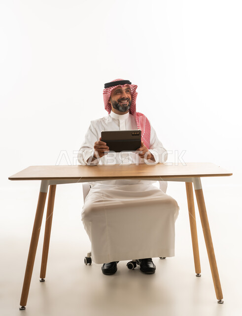 رجل سعودي مع جهاز لوحي على مكتب عمل خلفية بيضاء