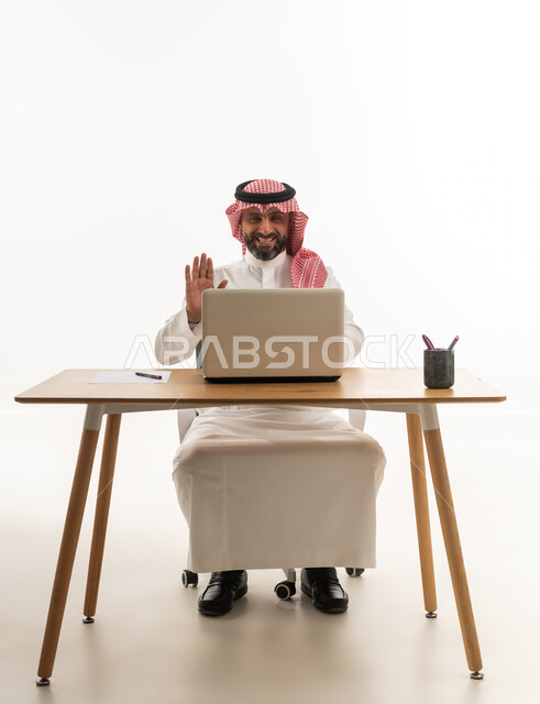 Saudi Man at Desk Waving During Laptop Video Call
