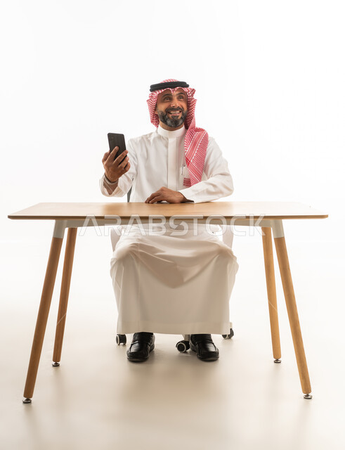 Saudi Man with Smartphone at Office Desk