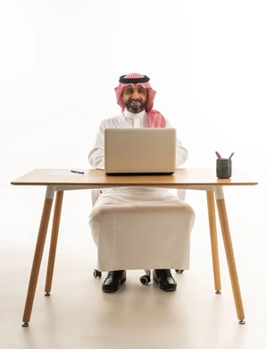 رجل أعمال سعودي يستخدم اللابتوب على مكتبه