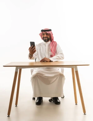 رجل سعودي يستخدم الهاتف الذكي في المكتب