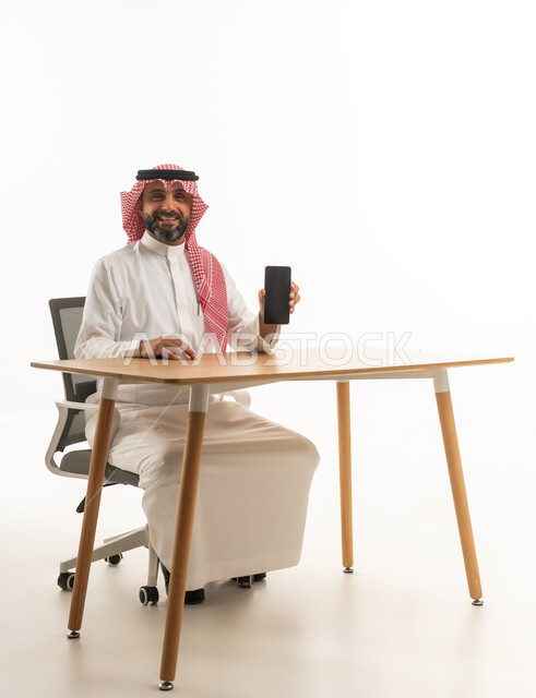 Saudi Businessman at Desk Holding Smartphone on White Background