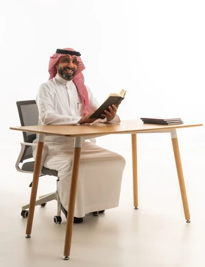 Saudi Man in Traditional Thobe Reading at Desk