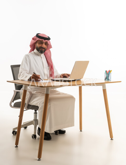 رجل أعمال سعودي يعمل على كمبيوتر محمول في المكتب