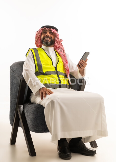 مهندس سعودي يرتدي سترة السلامة مع هاتف ذكي