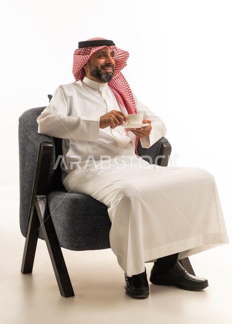 رجل سعودي بالزي التقليدي يحمل فنجان قهوة