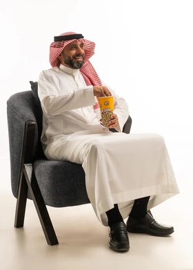 Saudi Man in Traditional Thobe Eating Popcorn