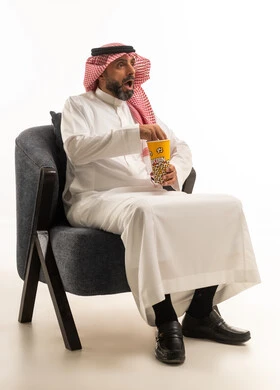 رجل سعودي بالثوب يشاهد فيلما بتعبيرات مندهشة