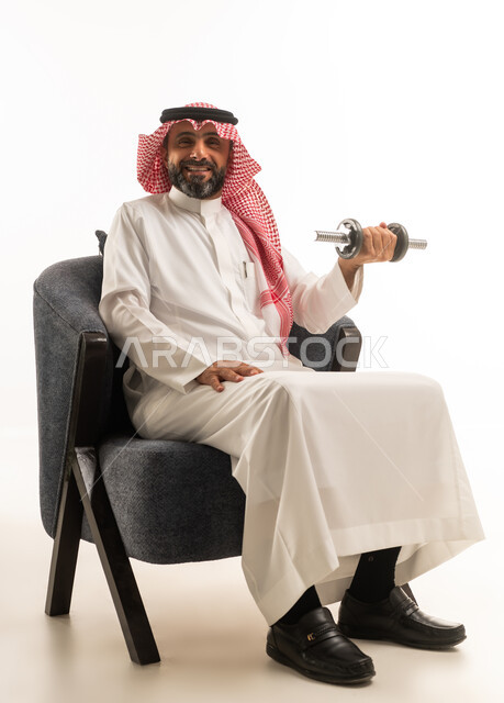 رجل سعودي بالزي التقليدي يمارس رياضة رفع الأثقال
