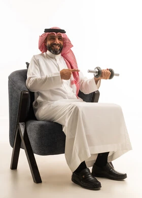 رجل سعودي بالثوب يحمل وزن رياضي بخلفية بيضاء