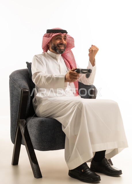 رجل سعودي ممسك بجهاز تحكم مع إيماءة نصر