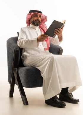 رجل سعودي بالزي التقليدي يقرأ كتاباً