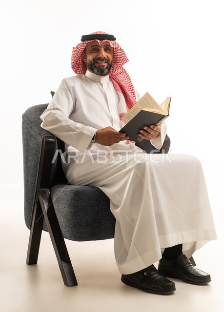 رجل سعودي يجلس على كرسي ويقرأ كتاباً