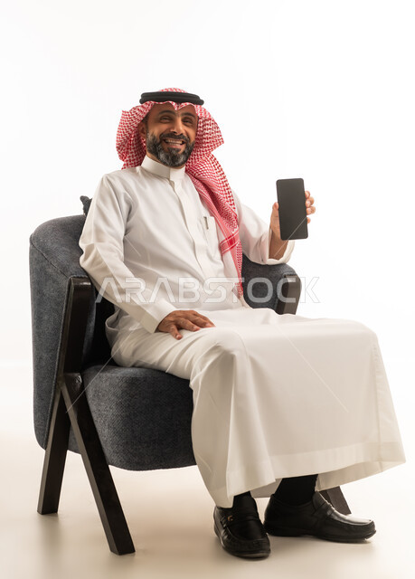 رجل سعودي بالزي التقليدي يمسك هاتف ذكي