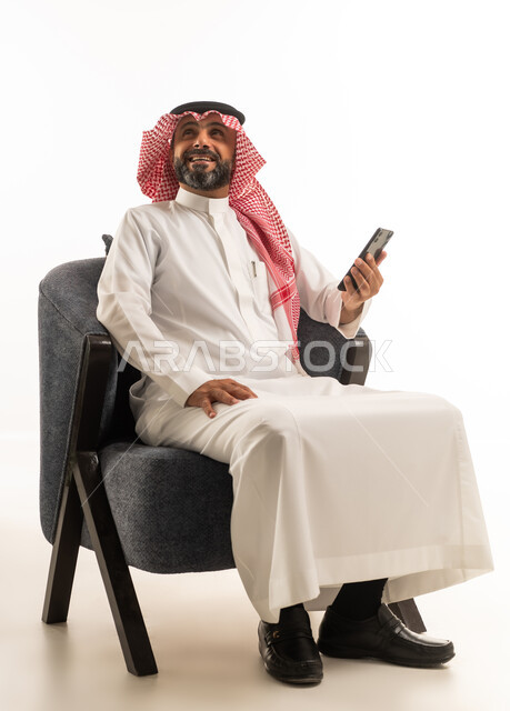 رجل سعودي بالزي التقليدي مع هاتف ذكي
