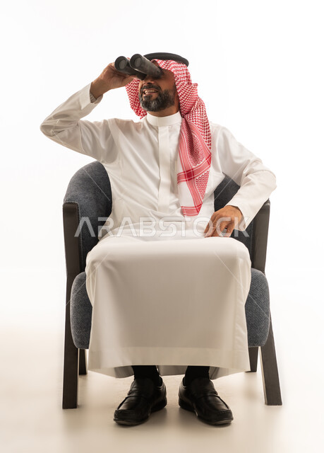 رجل سعودي بالثوب التقليدي يستخدم المنظار