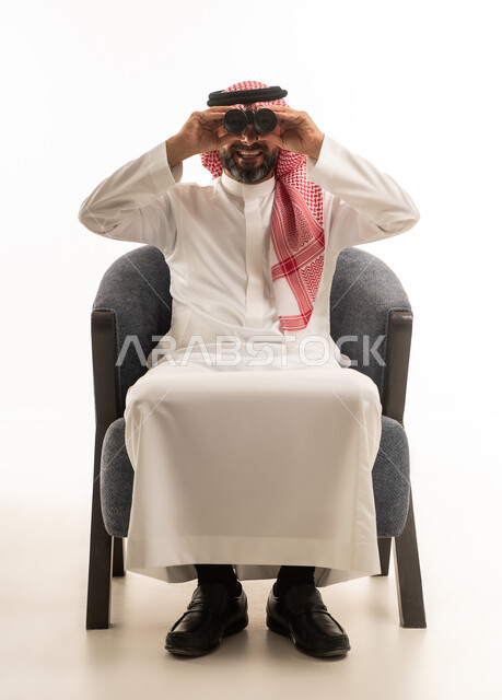 رجل سعودي مع منظار يجلس أمام خلفية بيضاء استوديو