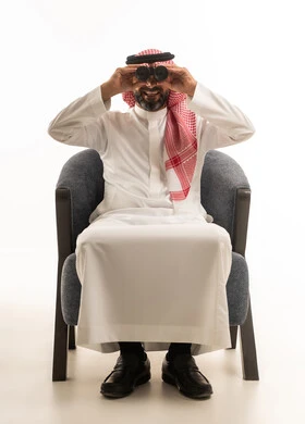 رجل سعودي مع منظار يجلس أمام خلفية بيضاء استوديو