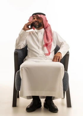 رجل سعودي يجلس على كرسي يتحدث بالهاتف المحمول