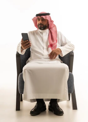 Saudi Man in Traditional Thobe Using Smartphone