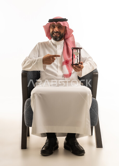 رجل سعودي يمسك ساعة رملية بخلفية بيضاء