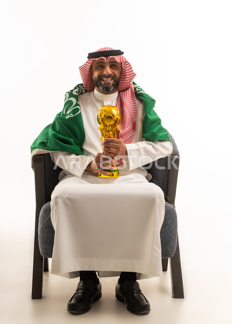 رجل سعودي يحمل كأس كرة القدم مع العلم الوطني