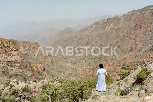 زاوية من الخلف لصبي خليجي ينظر لجمال مدينة الطائف ، جبال الشفا في مدينة الطائف بالمملكة العربية السعودية ، أماكن سياحية بالسعودية ، جو ضبابي على جبال الطائف ، المرتفعات الجبلية ، مناظر طبيعية جبلية في مدينة الطائف ، جبال الطائف