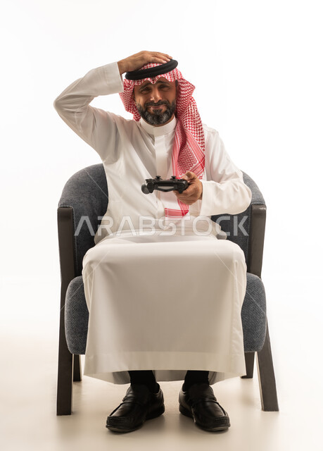 رجل سعودي يحمل جهاز تحكم ألعاب بتعبير محبط