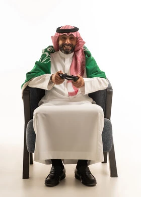 رجل سعودي يلعب ألعاب الفيديو مع العلم الوطني