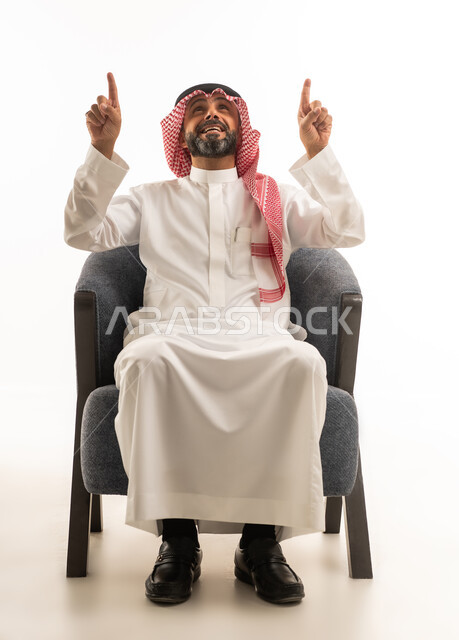 رجل سعودي يبتسم ويشير للأعلى بخلفية بيضاء