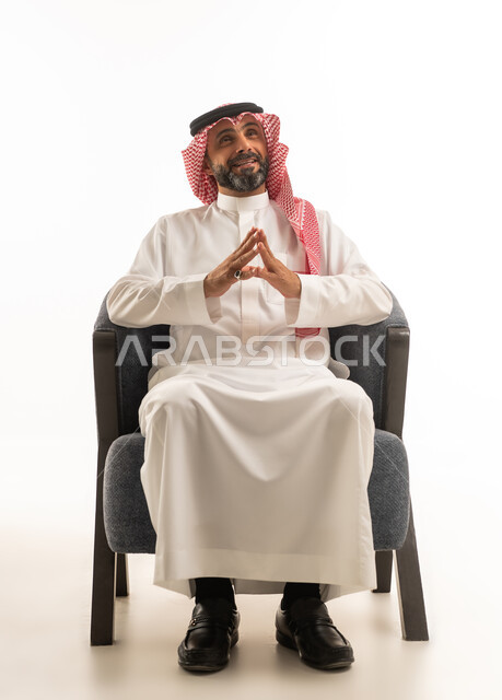 رجل سعودي بالزي التقليدي يجلس على كرسي
