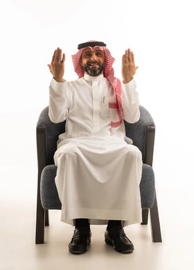 Saudi Man in Traditional Dress Praying in Armchair