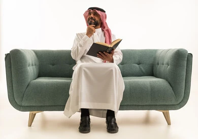 Saudi Man Reading Book on Sofa Thinking