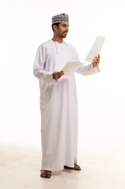رجل عماني بالزي التقليدي يمسك أوراقاً بيضاء