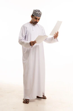 رجل عماني بالزي التقليدي يراجع الأوراق الرسمية