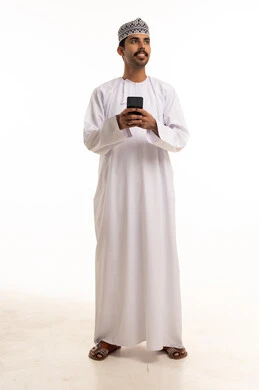 رجل عماني بالزي التقليدي يستخدم الهاتف الذكي