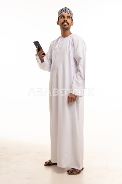 Omani Man in Traditional Dishdasha Holding Smartphone