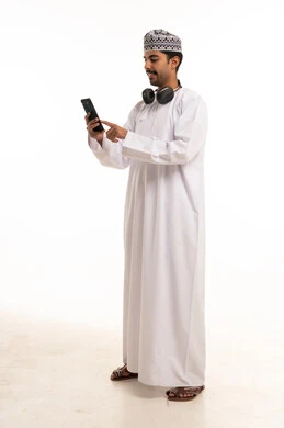 رجل عماني يستخدم الهاتف الذكي على خلفية بيضاء