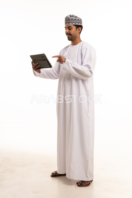 رجل عماني يستخدم جهاز لوحي على خلفية بيضاء