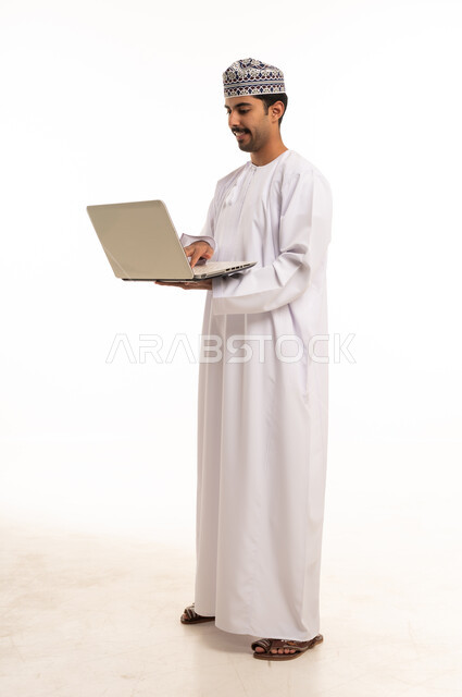 رجل عُماني بالزي التقليدي يستخدم اللابتوب