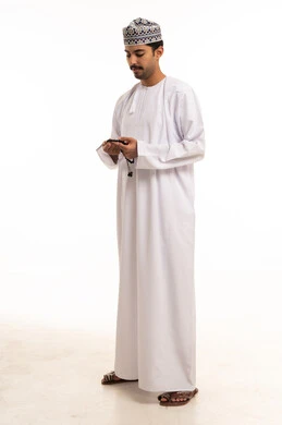 رجل عماني بالزي التقليدي والكمة يستخدم السبحة