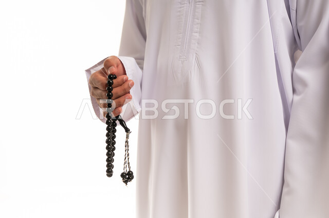 رجل عربي يرتدي الثوب التقليدي ويمسك مسبحة سوداء بخلفية بيضاء