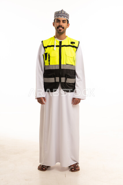 An Omani engineer in safety attire looks with gestures of happiness.