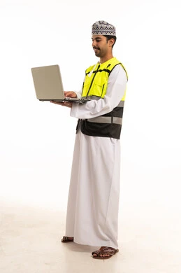 رجل عماني يرتدي سترة السلامة ويستخدم اللابتوب