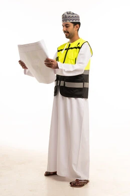 مهندس عماني يراجع المخططات الهندسية بزي السلامة