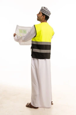 مهندس عماني يمسك مخططاً هندسياً بسترة سلامة