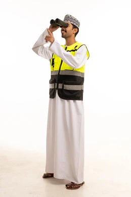 رجل عماني يرتدي سترة سلامة وينظر عبر المنظار