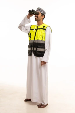 رجل عماني يرتدي سترة سلامة ويستخدم المنظار