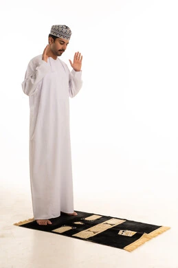 رجل عماني يؤدي الصلاة على خلفية بيضاء