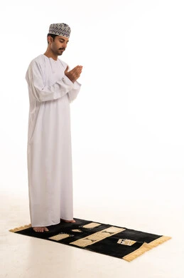 Omani Man in Traditional Dishdasha Praying on Rug